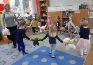 Dzieci tańczą w kole z pluszowymi misiami